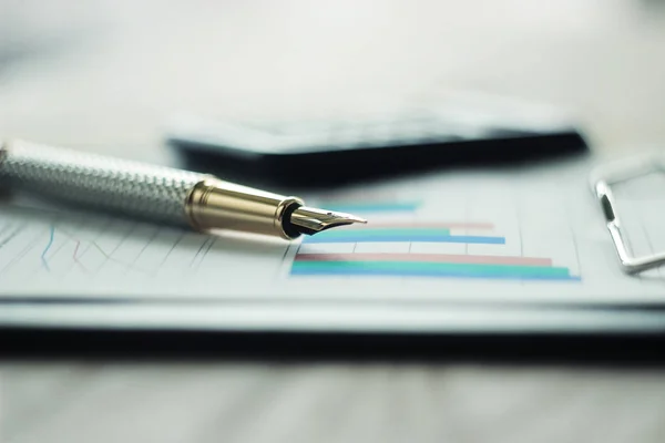 Ручка, калькулятор і фінансовий графік на робочому місці — стокове фото