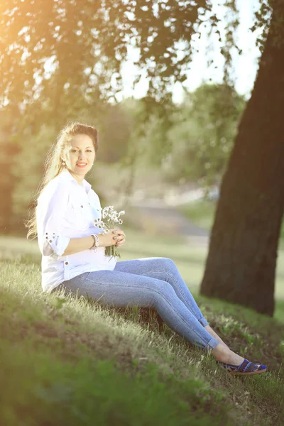 Nastávající matka sedí na trávě v parku za slunečného dne. — Stock fotografie