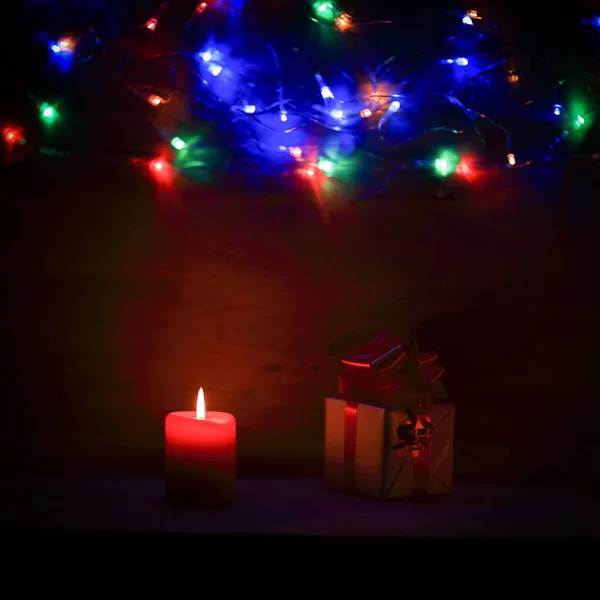 Zwei Kerzen und Weihnachtsgeschenk auf Feiertagshintergrund. — Stockfoto