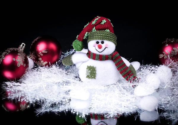 Divertente pupazzo di neve giocattolo e palla di Natale su uno sfondo nero . — Foto Stock