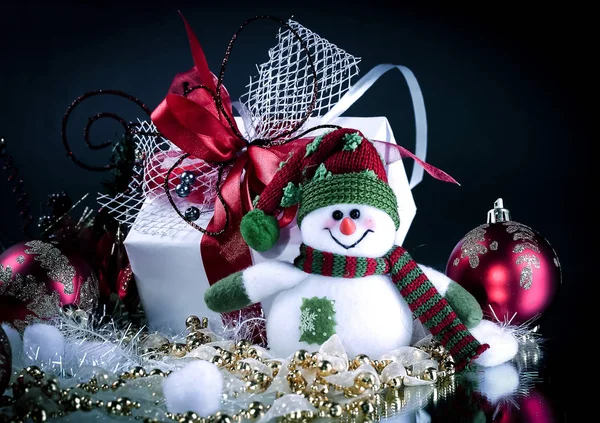 Carino pupazzo di neve scatola giocattolo con regali su uno sfondo nero . — Foto Stock