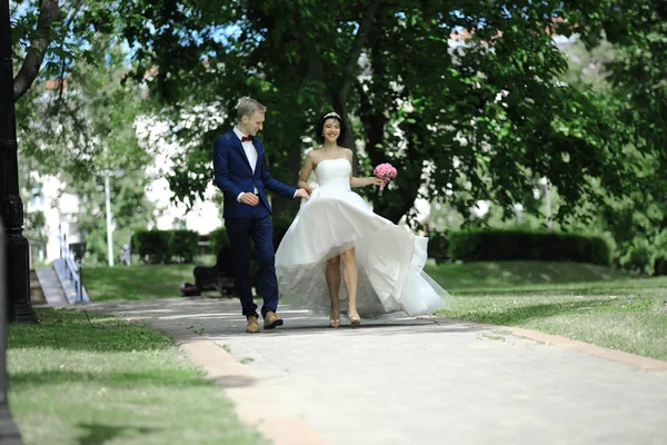 Brudgummen och bruden håller händer och promenader längs gränd — Stockfoto