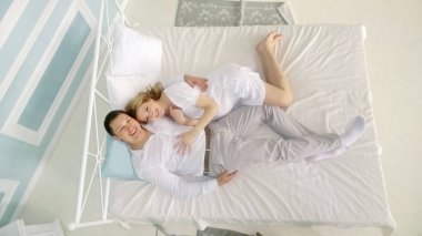 Gitarlı sevgili koca ve yatakta hamile karısı.