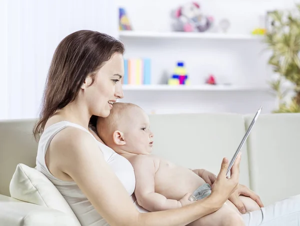 Happy mother showing his year-old baby pictures on digital tablet — Stock Photo, Image