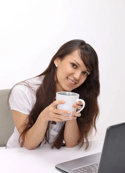 Młoda kobieta z filiżanką herbaty siedzi w miejscu pracy — Zdjęcie stockowe