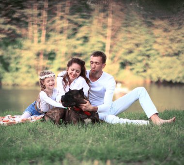 Güneşli bir yaz gününde piknikte köpekli mutlu bir aile. pregn