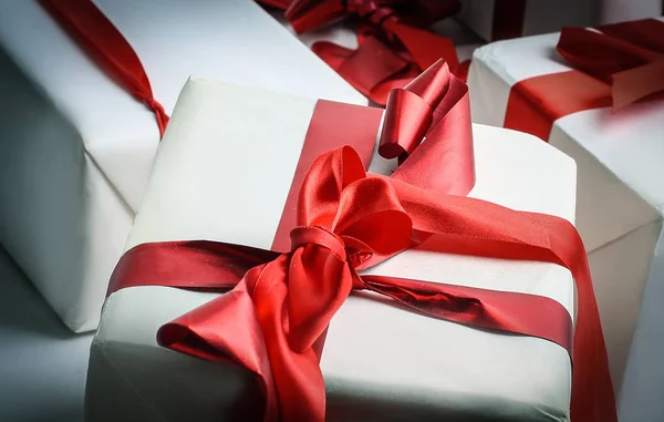 Elegantes cajas de regalo con cinta de satén rojo envueltas en papel . — Foto de Stock