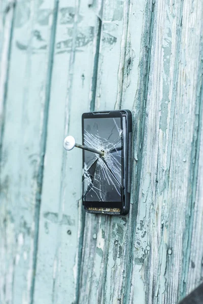 Conceito de tecnologia obsoleta: telefone celular pregado na cerca de um prego grande — Fotografia de Stock