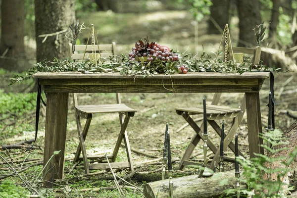 Frutas, ramas de olivo y velas en la mesa de picnic en el bosque — Foto de Stock