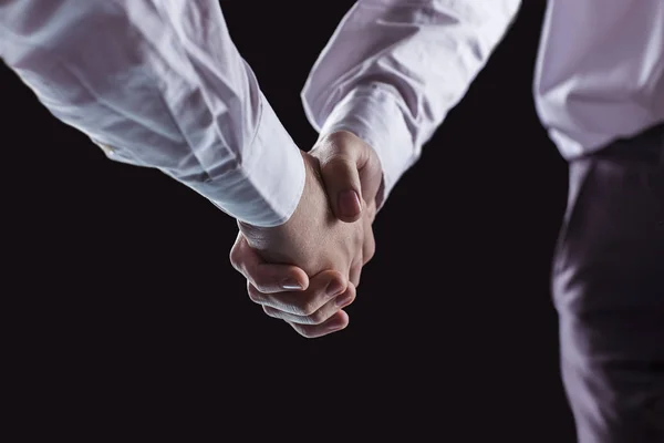 Concept of a reliable partnership: a close-up of handshake of business partners on a black background. — Stock Photo, Image