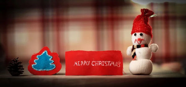 Fondo festivo. muñeco de nieve de juguete y las palabras feliz Navidad en —  Fotos de Stock
