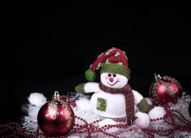 eğlenceli oyuncak kardan adam ve siyah arka planda Noel süslemeleri