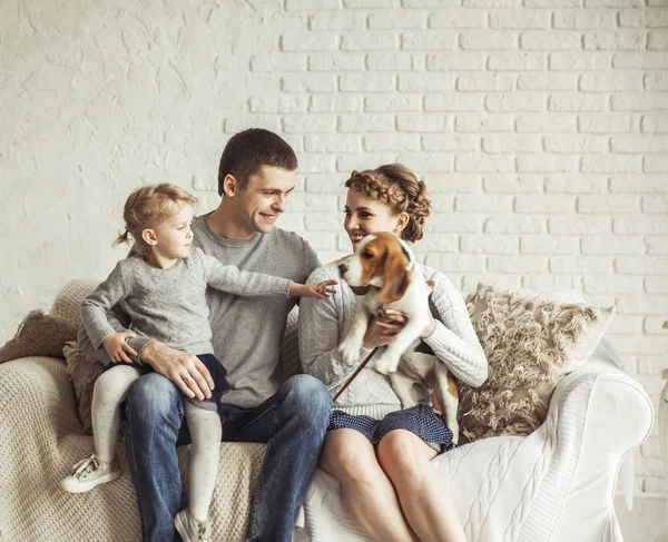 Retrato de una familia feliz y una mascota sentada en un sofá — Foto de Stock