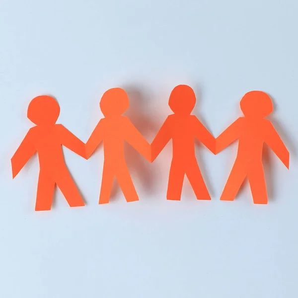 Four paper men taking each others hands — Stock Photo, Image
