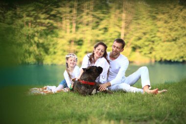 Güneşli bir yaz gününde piknikte köpekli mutlu bir aile. pregn