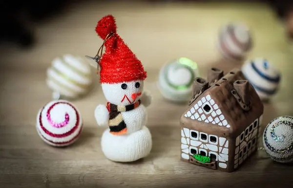 Speelgoed sneeuwpop en peperkoek huis aan de kersttafel — Stockfoto