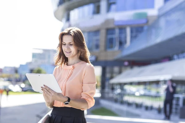 Exitosa mujer de negocios con tableta digital de pie frente a un gran edificio de oficinas moderno — Foto de Stock