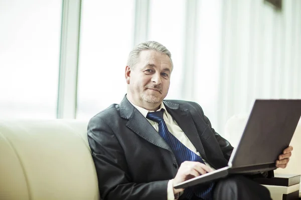 Erfahrener Geschäftsmann am Laptop sitzend auf dem Sofa in einem privaten Büro — Stockfoto