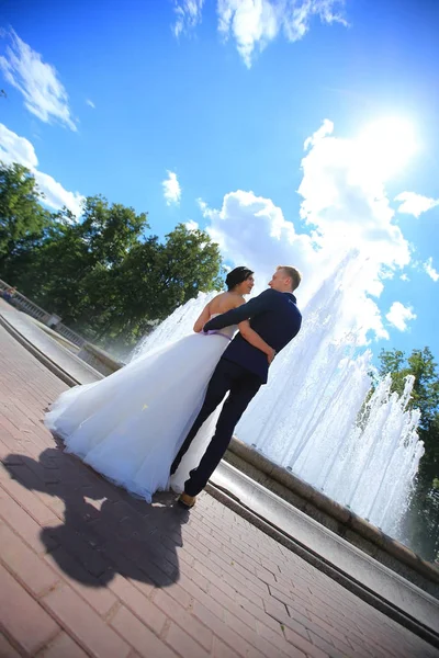 Bruid en bruidegom knuffelen en permanent in een openbaar plein — Stockfoto