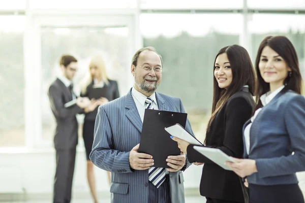 Succesvol zakenman en zijn twee assistenten met documenten op de achtergrond van het moderne kantoor — Stockfoto