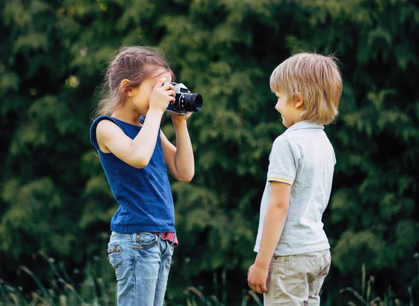 Oudere zus neemt een foto van zijn broer op de achtergrond van het Park — Stockfoto