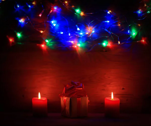 Zwei Kerzen und Weihnachtsgeschenk auf Feiertagshintergrund. — Stockfoto