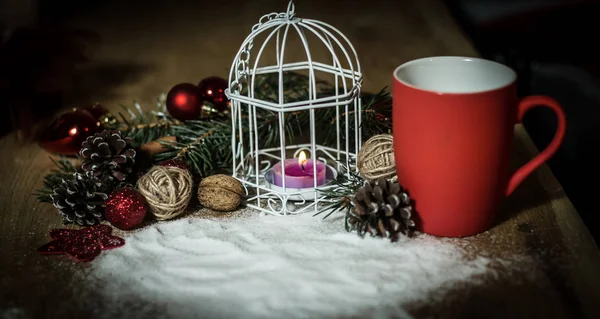 Красная чашка и свеча за рождественским праздничным столом — стоковое фото