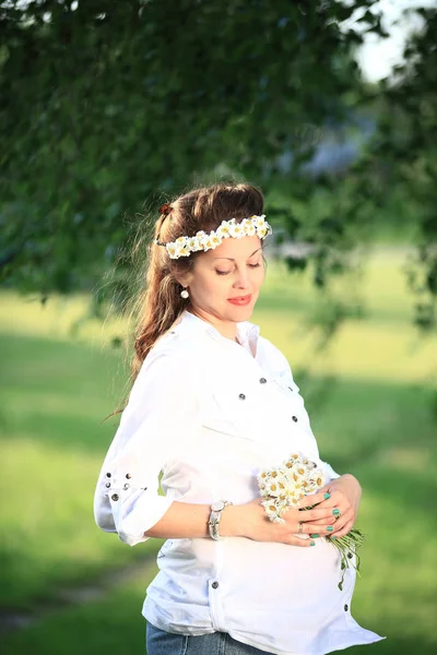 Donna incinta felice in una ghirlanda e un mazzo di fiori selvatici o — Foto Stock