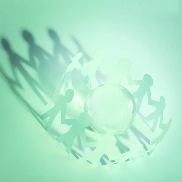 glass globe and a family of paper men on a green background