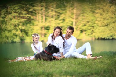 Güneşli bir yaz gününde piknikte köpekli mutlu bir aile. pregn