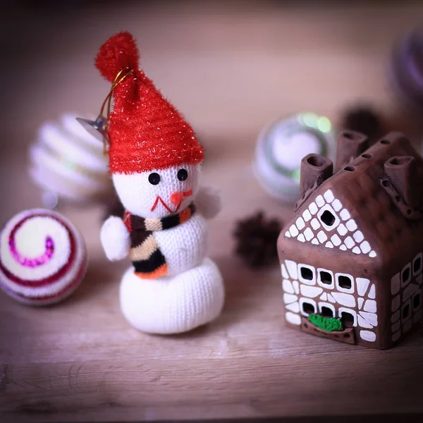 Muñeco de nieve de juguete y casa de jengibre en la mesa de Navidad —  Fotos de Stock