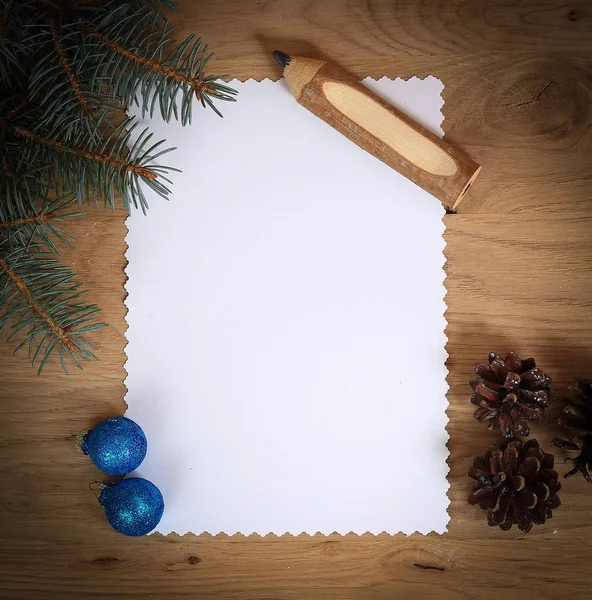 Чистая рождественская открытка, сосновые шишки и карандаш на деревянной спинке — стоковое фото