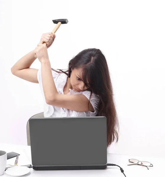 Joven mujer de negocios rompiendo un ordenador portátil sentado detrás de un escritorio . — Foto de Stock