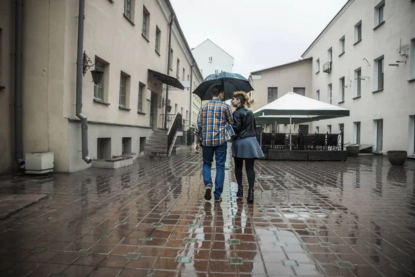 Feliz pareja amorosa está bajo un paraguas en una calle de la ciudad en un día lluvioso — Foto de Stock