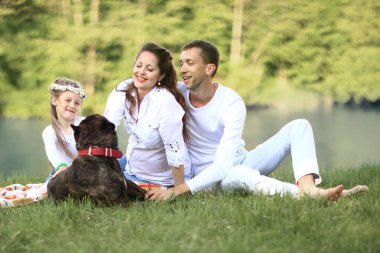 Güneşli bir yaz gününde piknikte köpekli mutlu bir aile. pregn