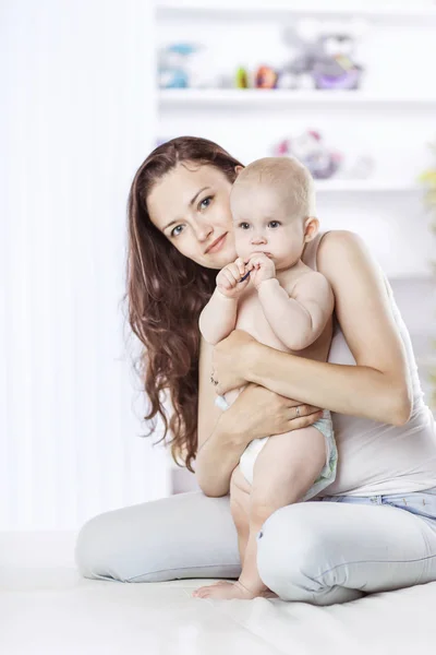 Portret van gelukkige moeder met een jaar oude peuter op de achtergrond van een kamer childs — Stockfoto