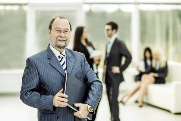 Portrait of successful businessman with documents on the background of business team and office — Stock Photo, Image