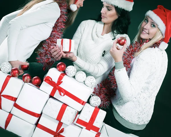 Three happy young girls dressed as Santa Claus sitting with a bu — Stock Photo, Image