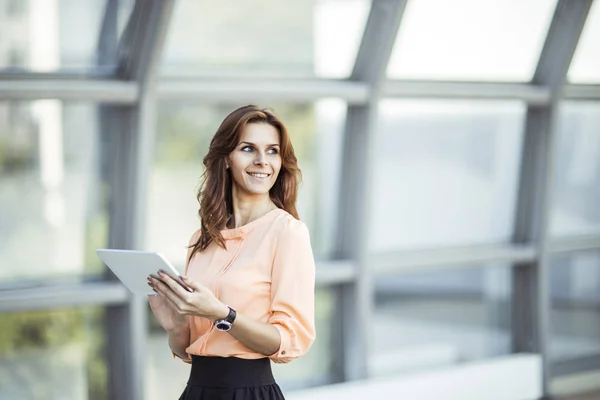 Успешная деловая женщина с цифровым планшетом, стоящая возле большого окна в современном офисе — стоковое фото