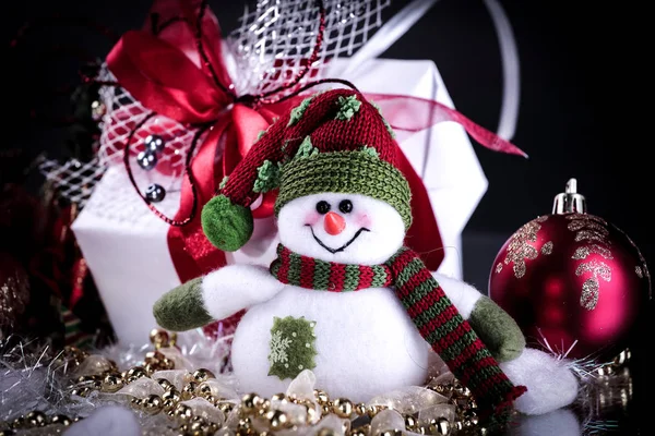 Leuke speelgoed vak sneeuwpop met giften op een zwarte achtergrond. — Stockfoto