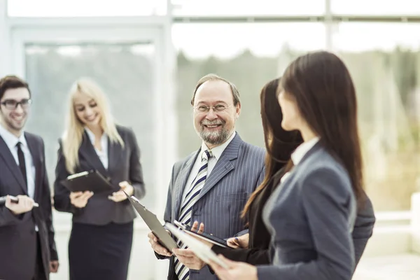 Portrait of successful businessman on the background of business team and office — Stock Photo, Image