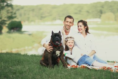 Güneşli bir yaz gününde piknikte köpekli mutlu bir aile. pregn