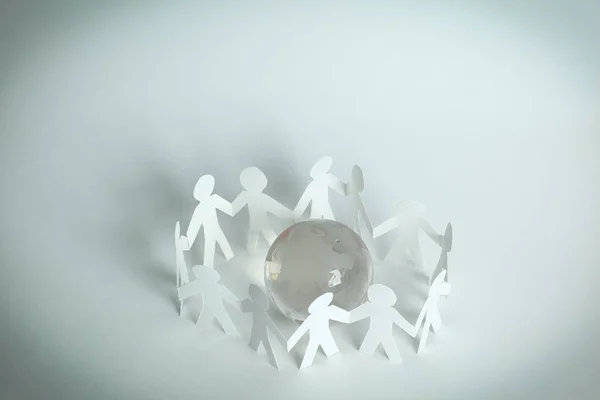 Team paper men standing around the glass globe. — Stock Photo, Image