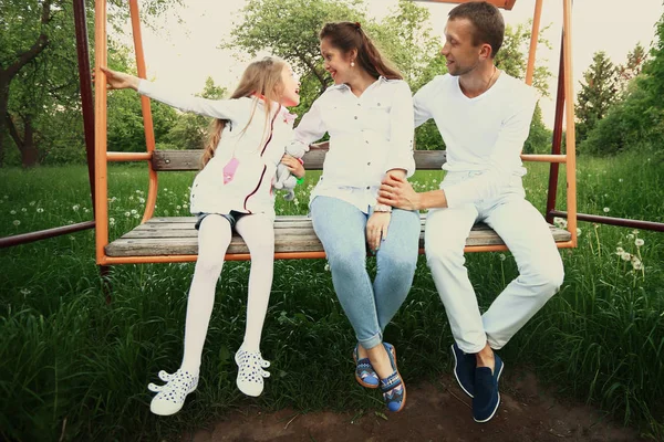 Familia feliz en los columpios en el jardín el domingo — Foto de Stock