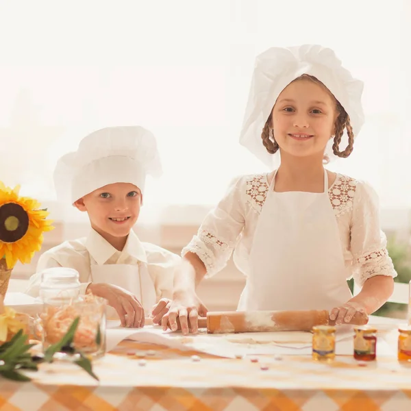 Счастливые маленькие дети в форме шеф-повара, чтобы приготовить вкусную еду — стоковое фото