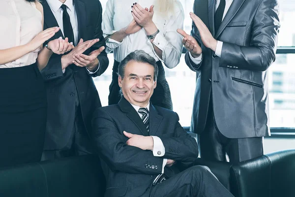 Experienced businessman at the age of applause in the background of their employees — Stock Photo, Image