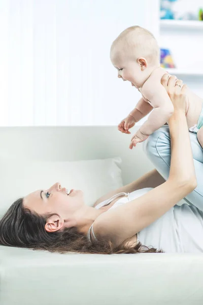 Concept van het moederschap: gelukkige moeder spelen met een jaar oude baby in de kamer voor kinderen — Stockfoto