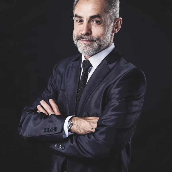 portrait of successful businessman with arms crossed on black background.