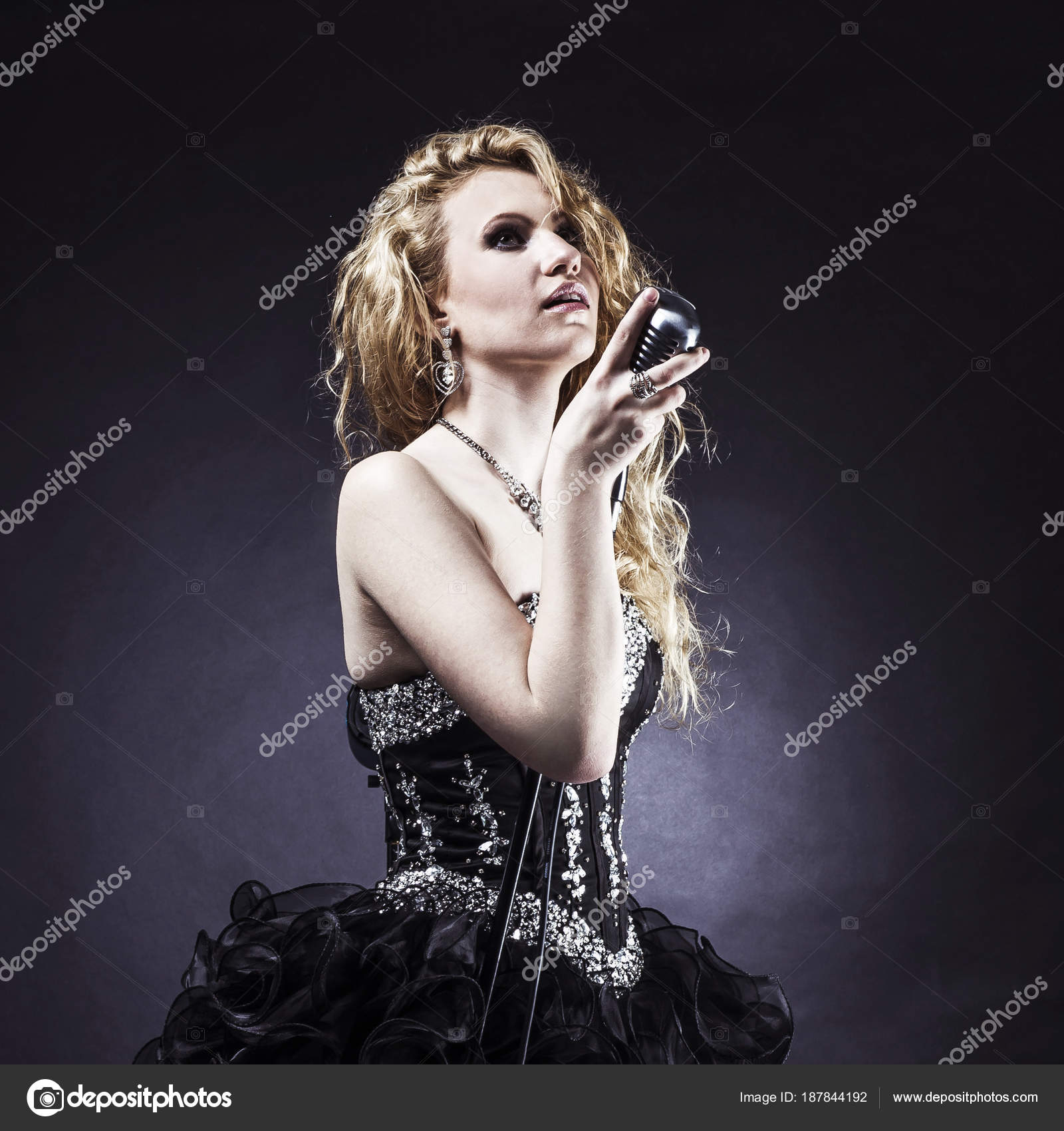 Beautiful Blonde Woman Singer In A Black Dress Holding A