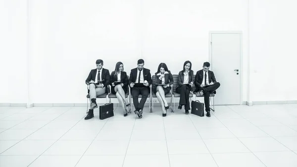 Equipe de negócios que trabalha com documentos antes da sessão de trabalho sentado em cadeiras de escritório em frente à sala de conferências — Fotografia de Stock